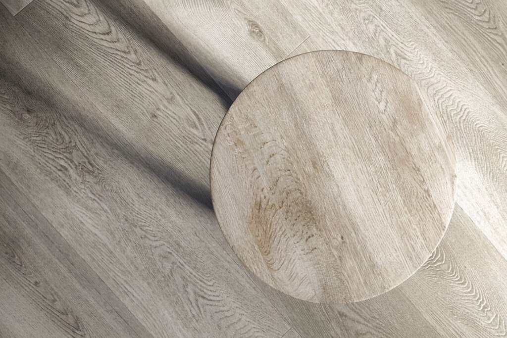 Round wooden table rests on a light, textured wood floor, showcasing natural grain patterns and a minimalist design.