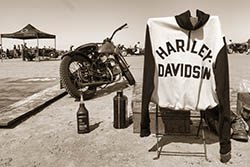 Vintage Harley-Davidson motorcycle with a branded jacket on a chair, showcased at a classic bike event.