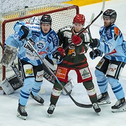 Hockey players from opposing teams battle energetically in front of the goal, competing intensely during the match.
